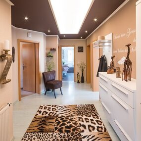 Afrikanisch inspirierter Flur mit Tierfellteppich, Holzdeko und moderner Beleuchtung.