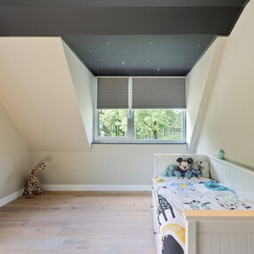 Modernes Kinderzimmer mit Dachschräge, Holzboden, Spielzeug und gemütlichem Tageslicht.