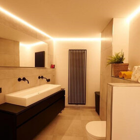 Modernes Badezimmer mit großem Spiegel, LED-Beleuchtung und stilvollem Waschbecken.