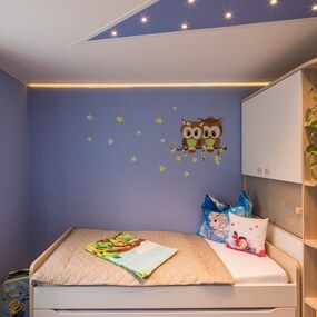 Modernes Kinderzimmer mit gemütlichem Bett, Eulen-Wanddeko und kindgerechter Einrichtung.